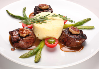 Filet mignon with asparagus and mashed potatoes on a white plate.