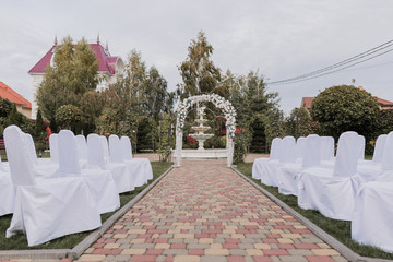 wedding ceremony arch decorated with flowers with chairs