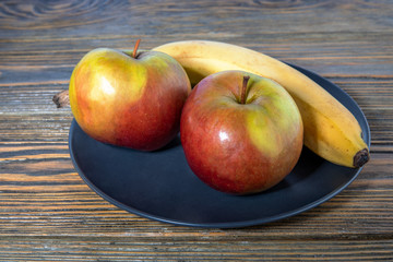 Apples and bananas in a plate on a vintage wooden table, healthy food. Healthy lifestyle concept.