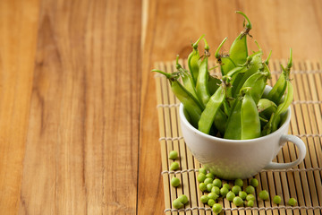 Peas placed in a cup on a wooden background