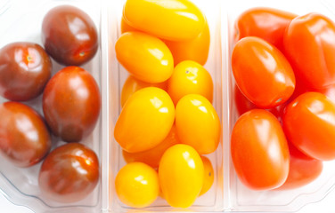 Vegetables, cherry tomatoes in three colors in a plastic transparent box, red, yellow and dark, top view