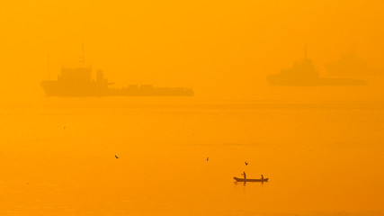Obraz premium Silhouettes on foggy sunrise at sea