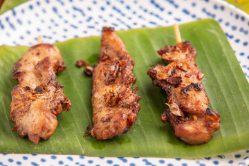 Grilled pork skewers put on the ground, green banana stump leaves