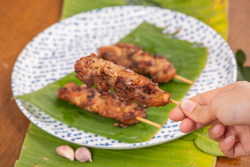 Grilled pork skewers put on the ground, green banana stump leaves