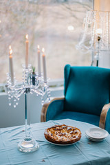 Rustic, traditional, apple pie on the blue table, blue chair and crystal lamp and candles