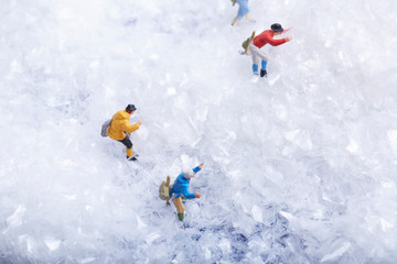 Miniature man climbing snow mountain