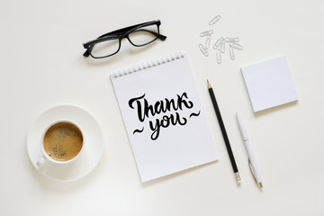 Workspace with pen, paper, coffee cup and office supplies.