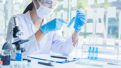 Medical or scientific researcher or man doctor looking at a test tube of clear solution in a...