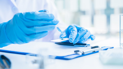 Medical or scientific researcher or man doctor looking at a test tube of clear solution in a...