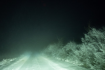 drifting snow on a small road at night