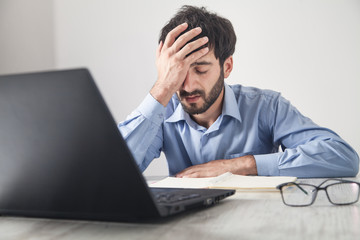 Caucasian stressed businessman sitting in office.