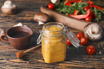 Jar of tasty honey mustard sauce on wooden table