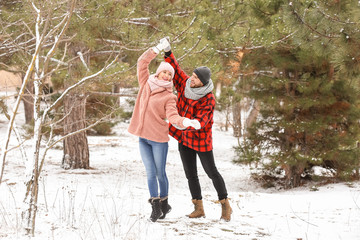 Happy young couple dancing in park on winter day