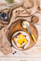 Tasty toasted bread with honey, butter and berries on table