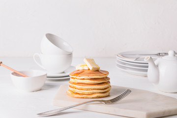 Tasty pancakes with honey and butter on table