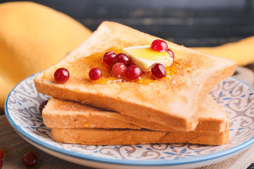 Tasty toasted bread with honey, butter and berries on plate