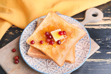Tasty toasted bread with honey, butter and berries on plate