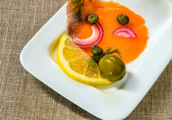 Close-up  top view on thinly slices of smoked salmon on white dish and gray linen napkin