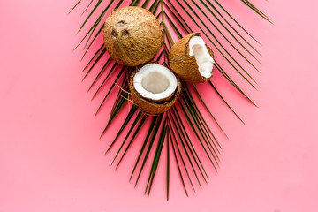 Exotic background with coconuts and palm leaves on pink background top-down frame copy space