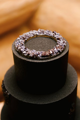 Large black chocolate three-tiered cake with caramel, unusual execution of the dessert