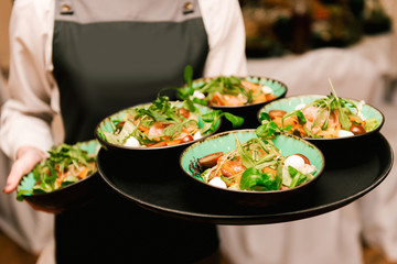 Salad with vegetables, herbs and cheese on a tray at the waiter