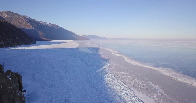 Frozen lake. Deep blue ice, hummocks, cracks Beautiful winter landscape with transparent smooth ice.