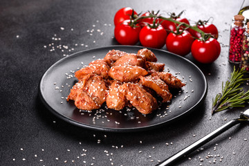Chicken fillet in sesame seeds, teriyaki sauce on a black stone plate
