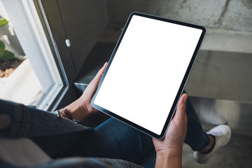 Mockup image of a woman holding black tablet pc with blank white screen in cafe