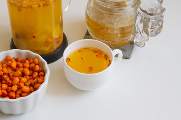 Vitamin useful sea buckthorn tea in a glass teapot with fresh sea buckthorn berries, orange, cinnamon sticks and honey. The concept of rest, relaxation. top view with a copy of the space
