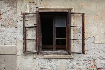 Old wooden window, open, no glass, just frame on an old abandoned building with weathered facade 