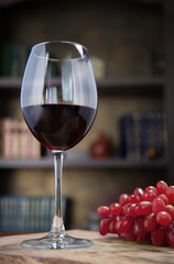 two glasses of red wine and grapes on wooden table