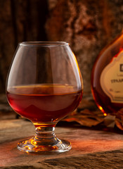 glass of brandy and cigar on wooden background