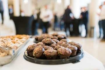 Chocolate muffins on table with people in background at hotel lobby.