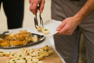 Close up of man scooping food by using utensil tong at buffet food restaurant catering self service table.