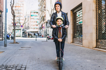 Mother and son riding an electric scooter with helmets