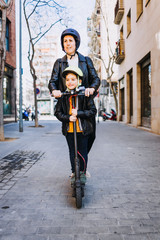 Mother and son riding an electric scooter with helmets