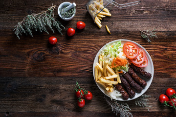 Spicy kofte (cevapcici, grilled minced meat) served with fresh tomatoes, lettuce, salad, vegetables...