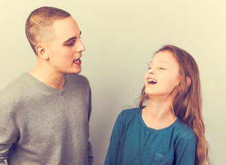 Young serious teen father have a dialog with his small school girl daughter. Happy joyful emotions on toned vintage color background.