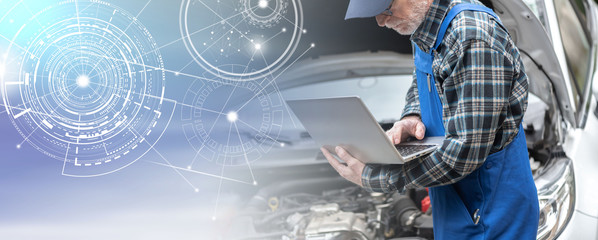 Mechanic using laptop for checking car engine; panoramic banner