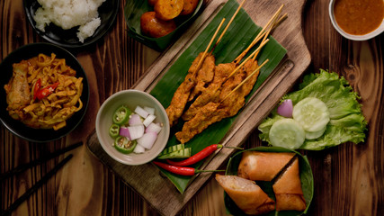 Top view of Thai traditional street food with pork satay with peanut sauce , Thai sausages, Khao Soi and fried spring rolls
