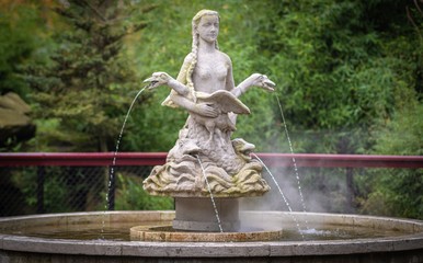 a beautiful fountain with statue of a woman with geese and frogs