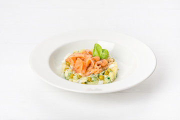 Salad with red fish, peas, fresh herbs in a white plate