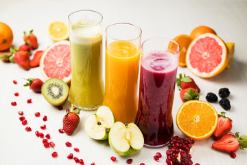 freshly squeezed juice, fruit and vegetable smoothies in glass glasses on a white table decorated with a composition of fruit