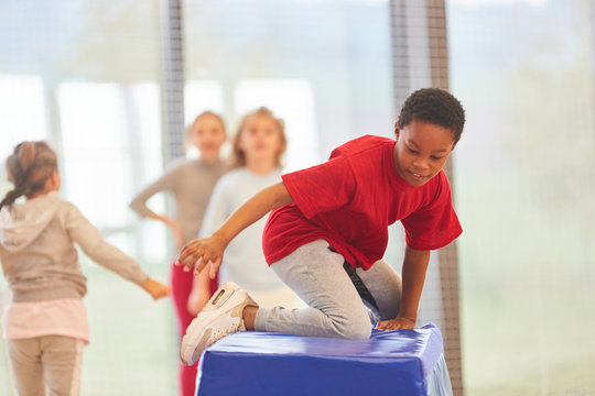 Kinder turnen an einem Sprungkasten