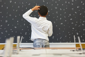 Afrikanischer Schüler steht vor Tafel in Grundschule