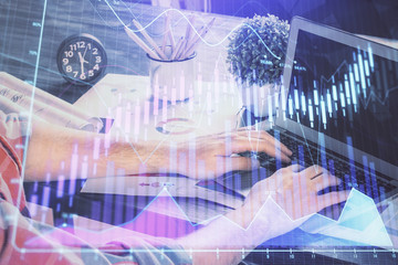 Double exposure of stock graph with businessman typing on computer in office on background. Concept of hard work.