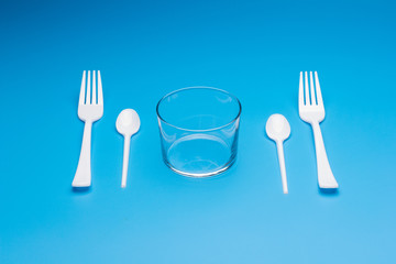 Teaspoon and plastic fork and glass tumbler