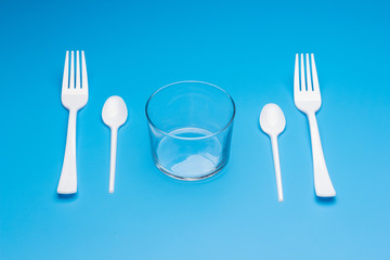 Teaspoon and plastic fork and glass tumbler