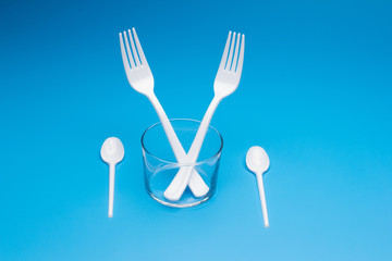 Teaspoon and plastic fork and glass tumbler