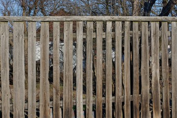 part of a gray rural fence from wooden boards on the street